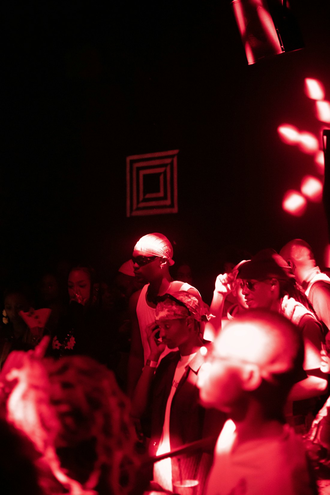 A crowd inside a dark club under red light.