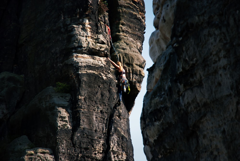 A climber high on an exposed rock face between two cliffs.